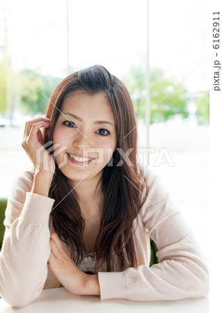 女性 対面 頬杖 正面 私服の写真素材