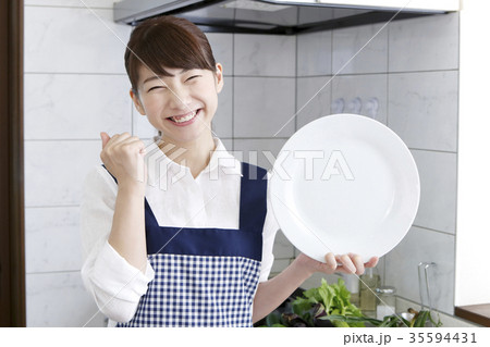女性 エプロン姿 白い皿 ガッツポーズの写真素材