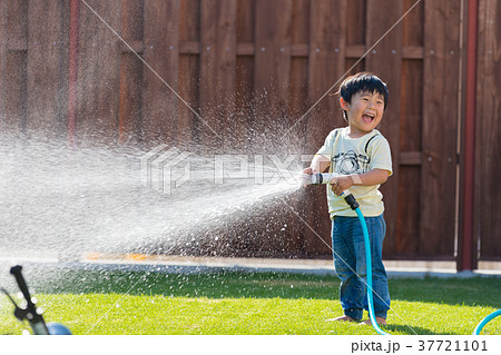 子供 水 水遊び ホースの写真素材