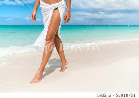 Woman walking on beach in blue fashion beachwear bathing suit and sarong  pareo sun skirt relaxing in luxury Caribbean vacation holidays. Summer or  winter getaway destination. Stock Photo