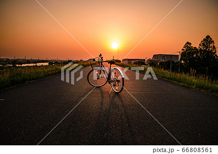 夕焼け 自転車 夕陽 土手 シルエット 影の写真素材