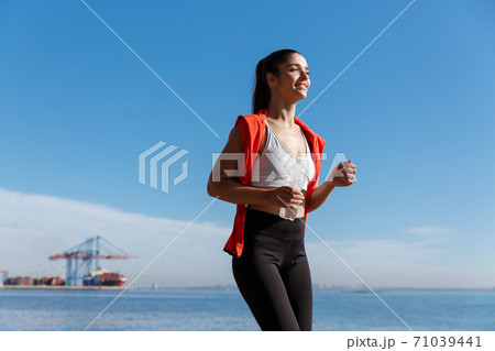 Side view of attractive and healthy fitness woman running along