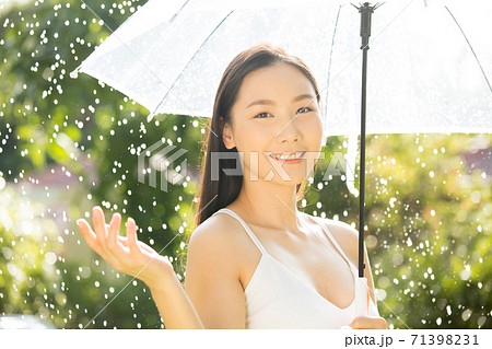 傘を持って雨の中を楽しむ綺麗な女性の写真素材