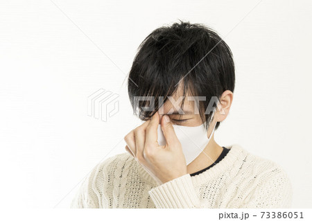 マスク姿の男性/頭痛で頭を抱える/具合が悪い独身男性/	
