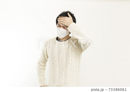 マスク姿の男性/頭痛で頭を抱える/具合が悪い独身男性/	