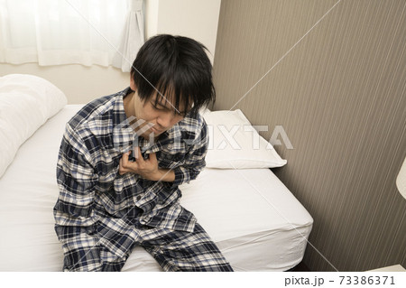 昨日の飲み会が遅くまで続き、朝胸焼けが酷く起きれないパジャマ姿の男性