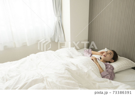 病気で寝込んでいる女性/体調の悪い女性/ベットに寝ている美しい女性