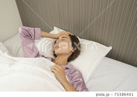 病気で寝込んでいる女性/体調の悪い女性/ベットに寝ている美しい女性