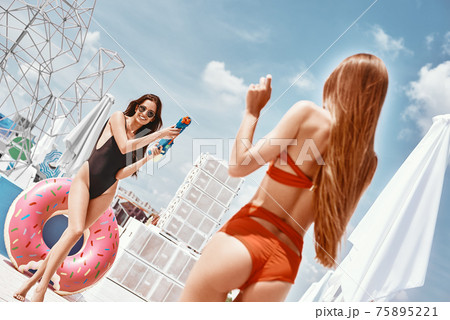 Three diverse young women in underwear holding hands and laughing