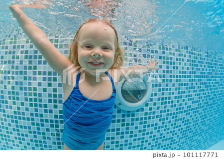 Smiling child in goggles swim, dive in the pool with fun - jump